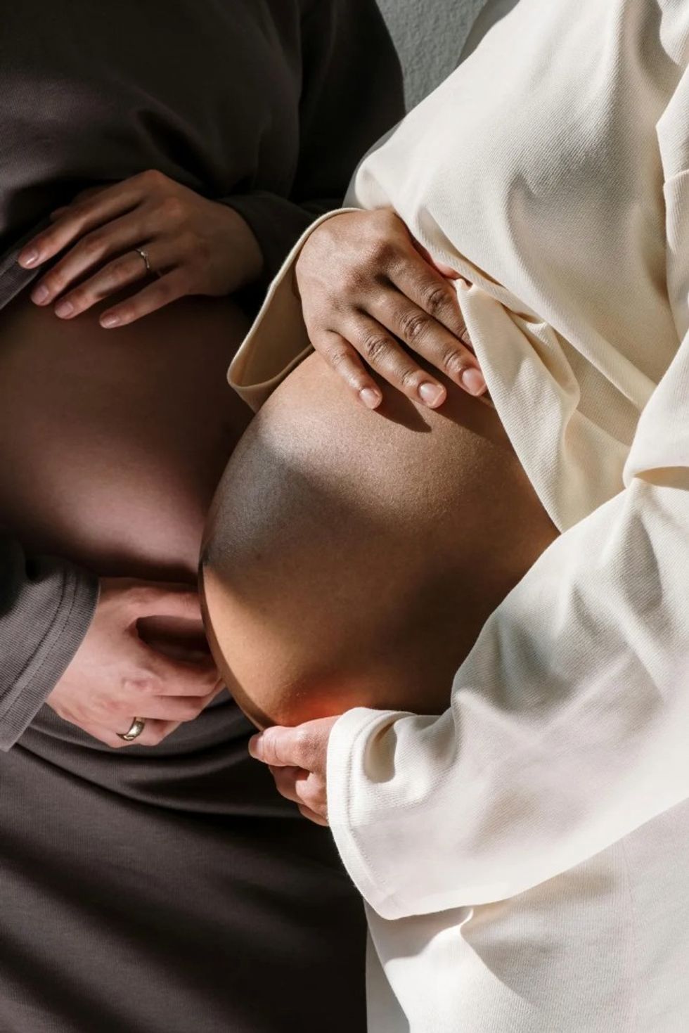 two pregnant women holding their baby bumps