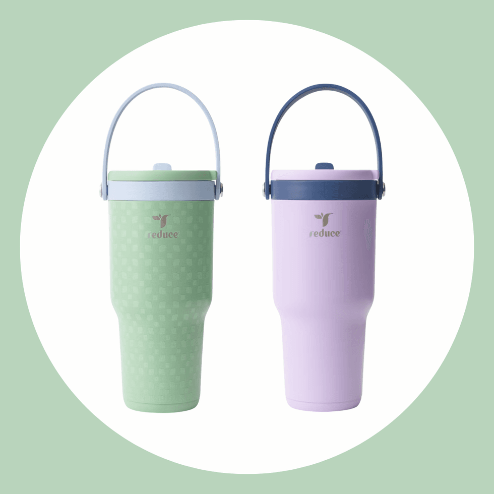 Two reusable cups with handles, one green and one pink, on a white circular background.