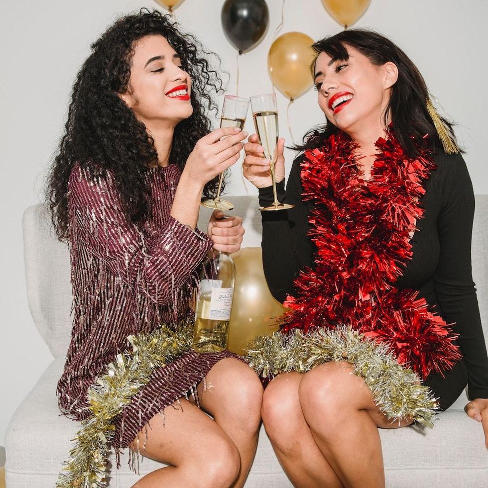 two women clinking their champagne at a holiday party