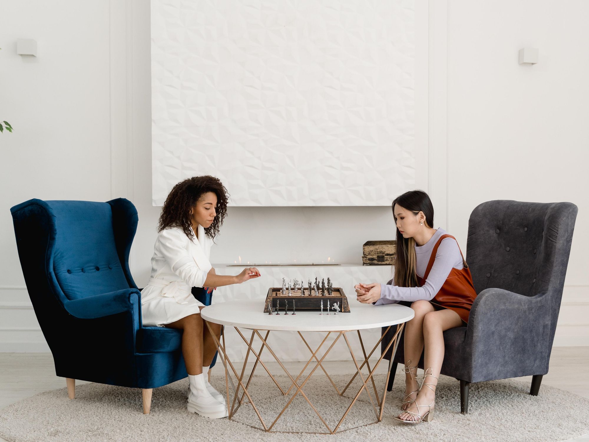 two women in large armchairs playing chess