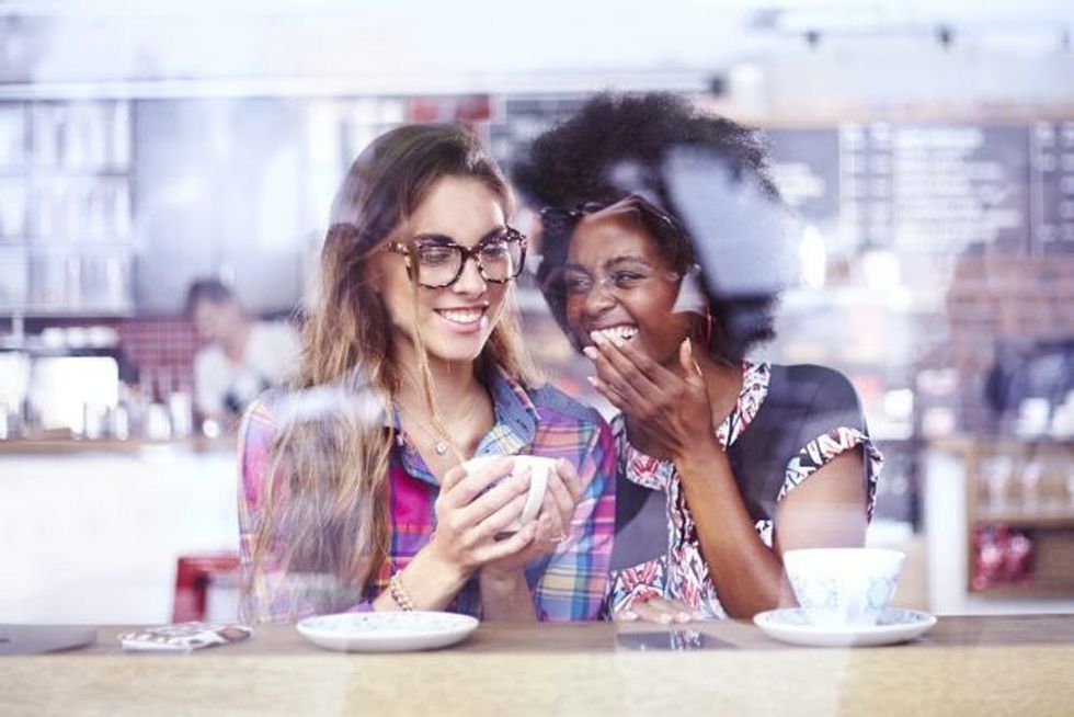 Two women laugh together in a cafe