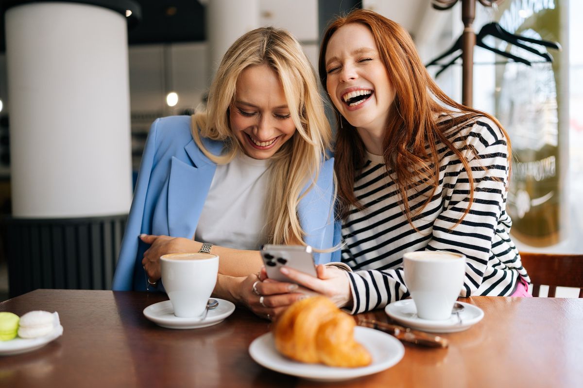 two women laughing at a coffee table showing off their good humor