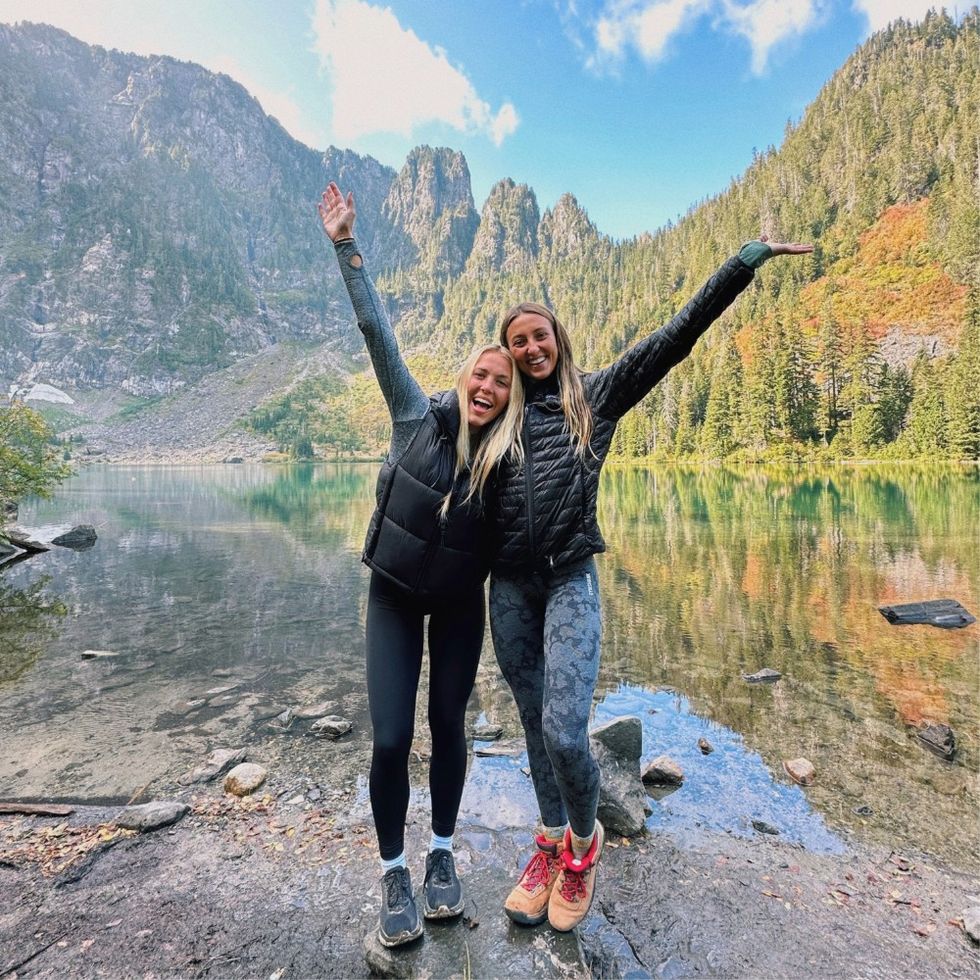 two women posing in front of a river in the woods