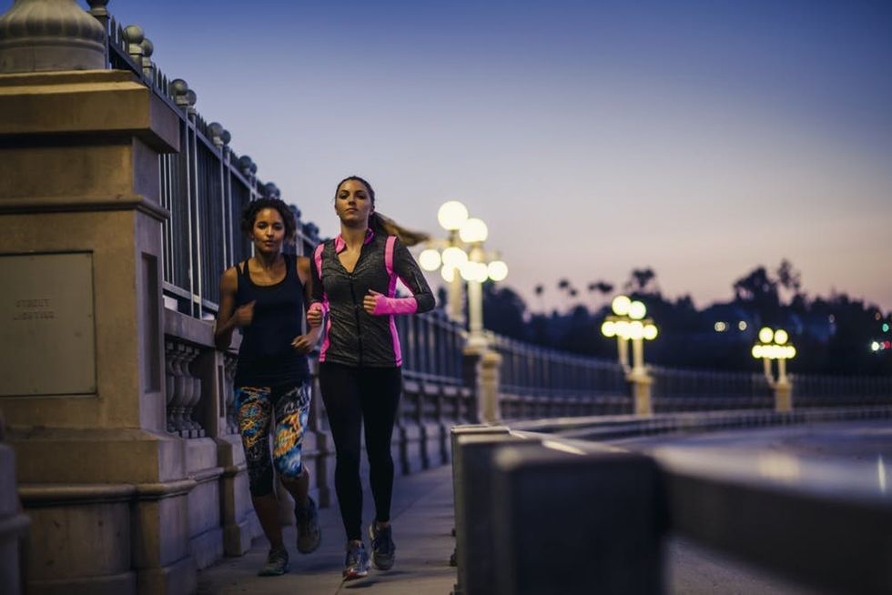 Two women run across a bridge in the evening