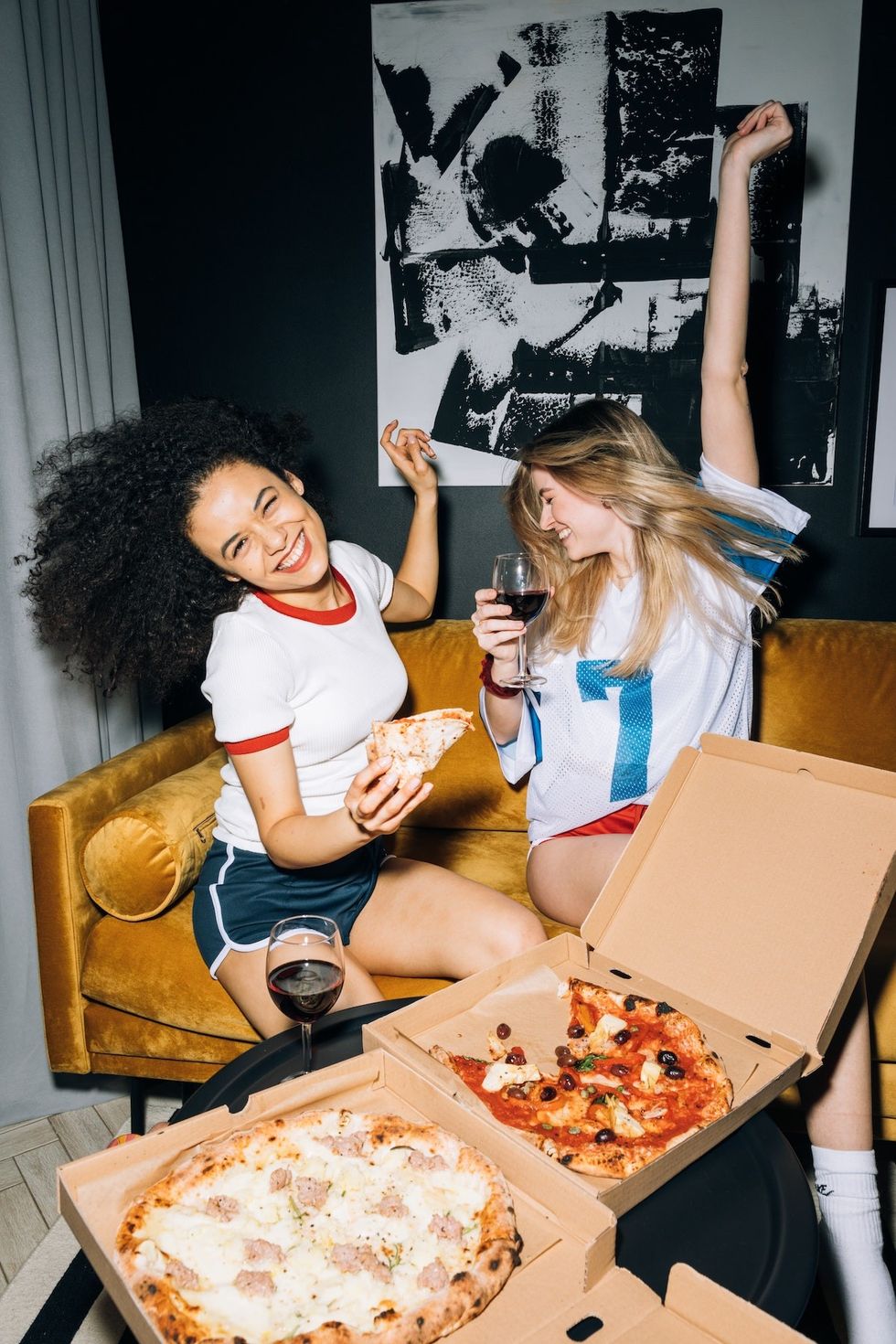 two women sharing wine and pizza together
