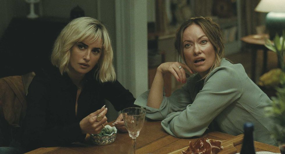 Two women sitting at a table, looking surprised or perplexed.