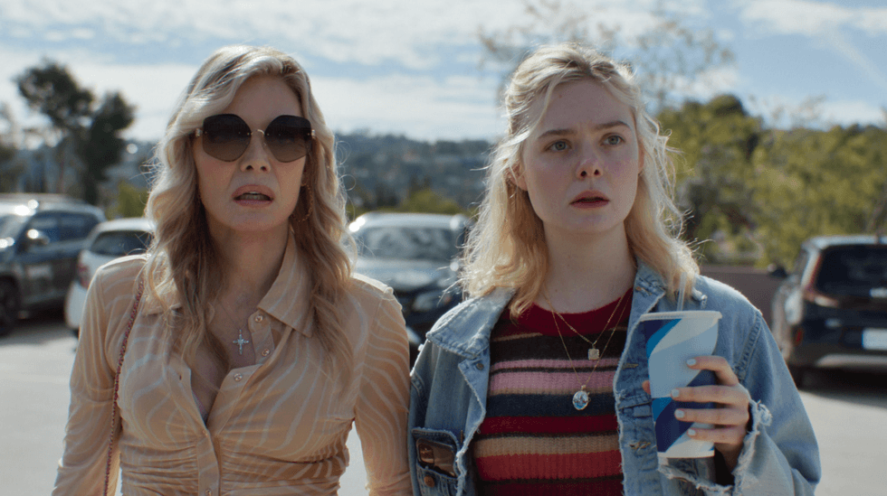 Two women stand outdoors, looking surprised; one holds a drink.