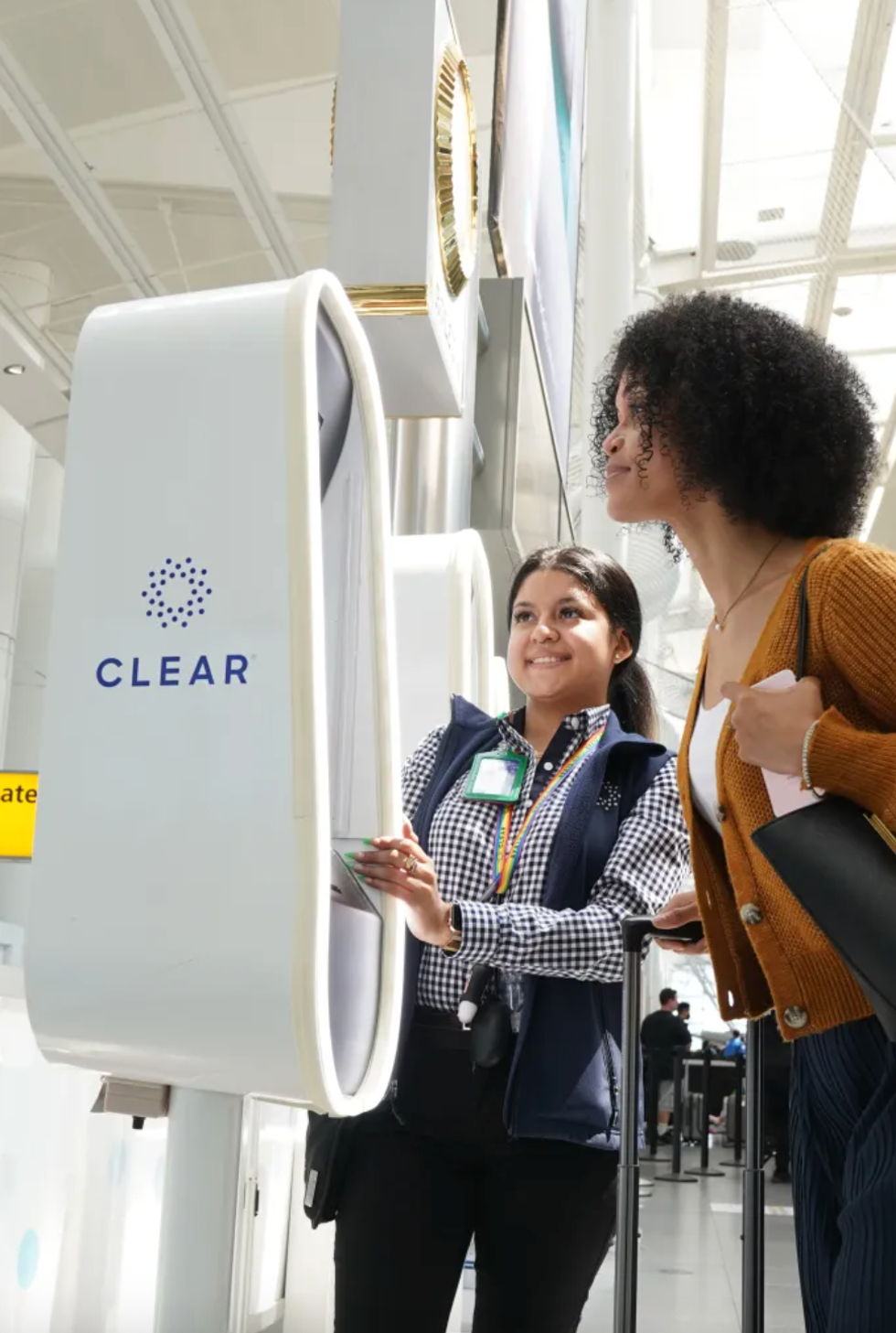 Two women using a CLEAR kiosk at an airport security checkpoint.
