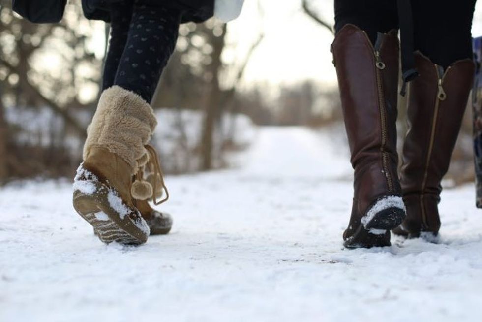 Two women walking on a snowcovered sidewalk.