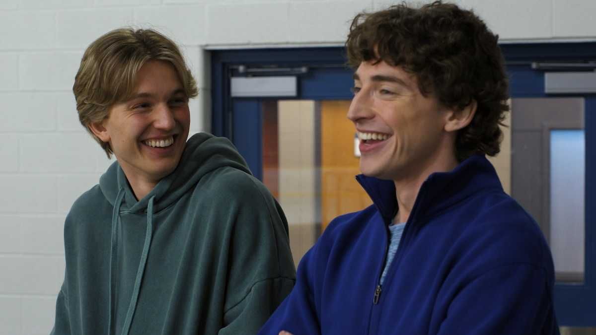 Two young men laughing together indoors.