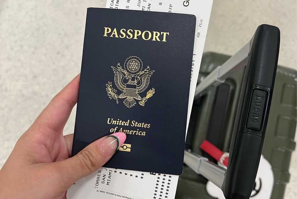 U.S. passport and boarding pass held above a suitcase handle.