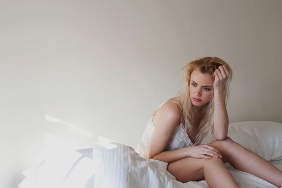 Upset young woman sitting on bed