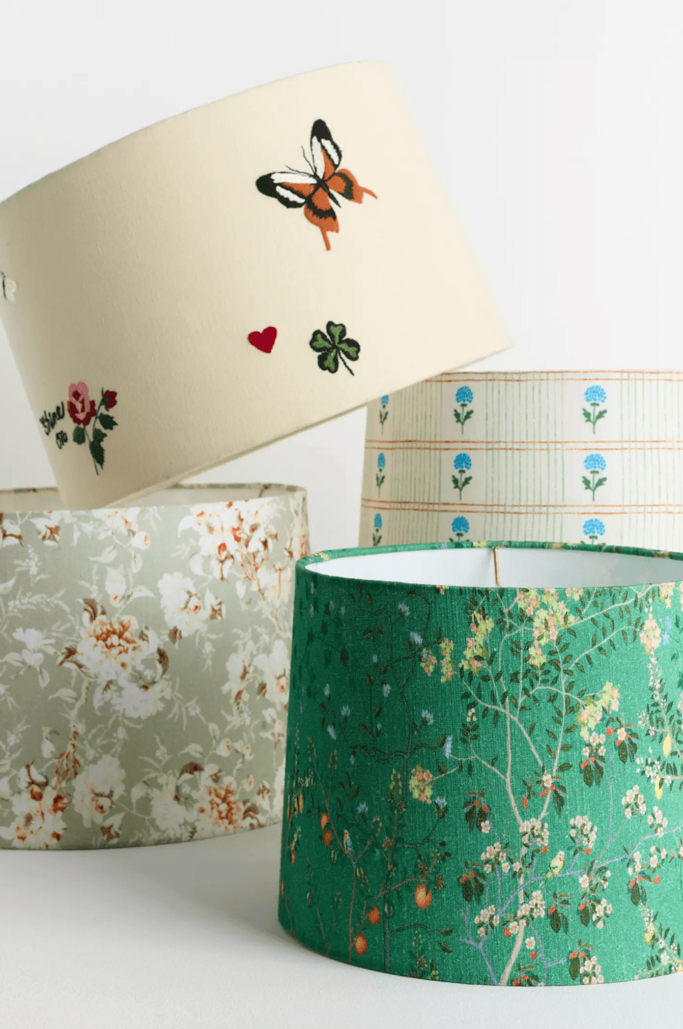 Various lampshades with floral and butterfly designs, arranged on a light surface.
