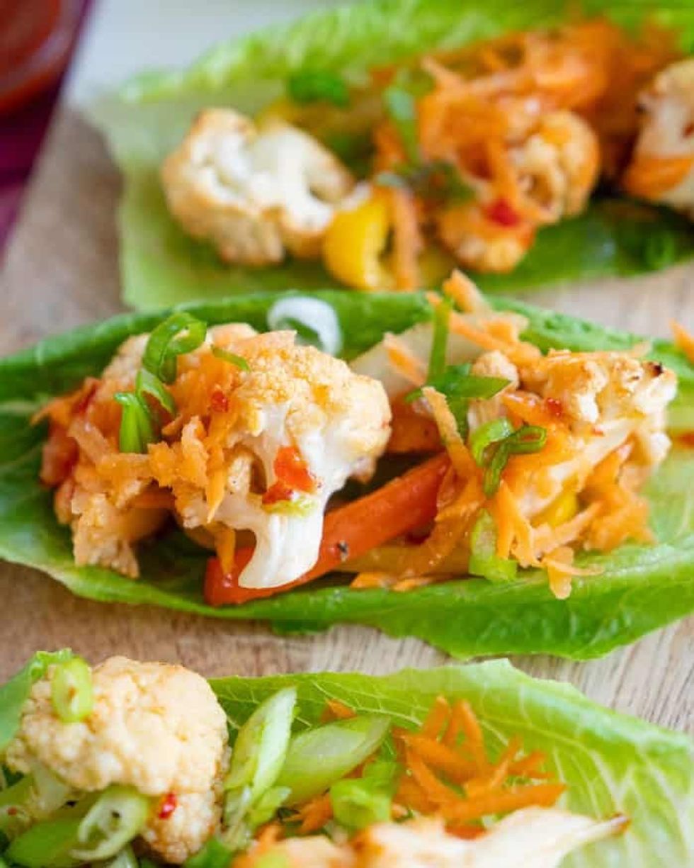Vegan Cauliflower Lettuce Wraps are sitting on a wooden surface.