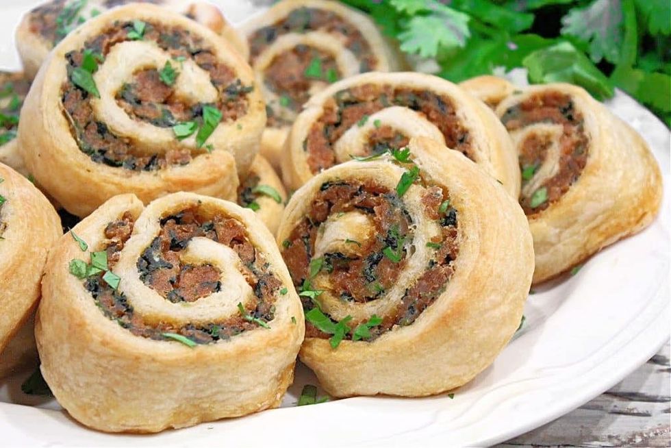 Vegan sausage pinwheels are on a white plate.