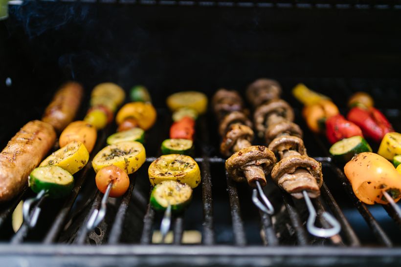 vegetable and meat skewers sitting on a grill