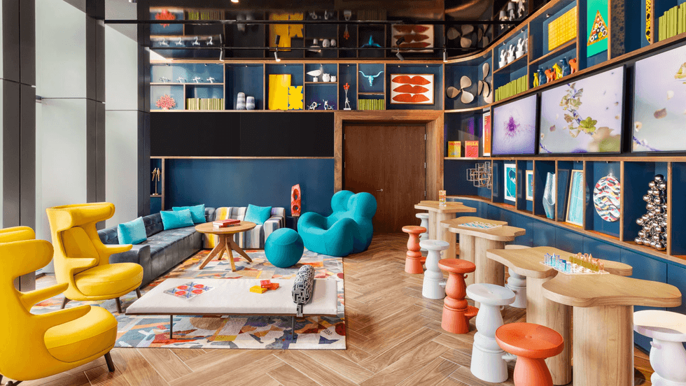 Vibrant room with colorful seating, abstract art, and display shelves under soft lighting.