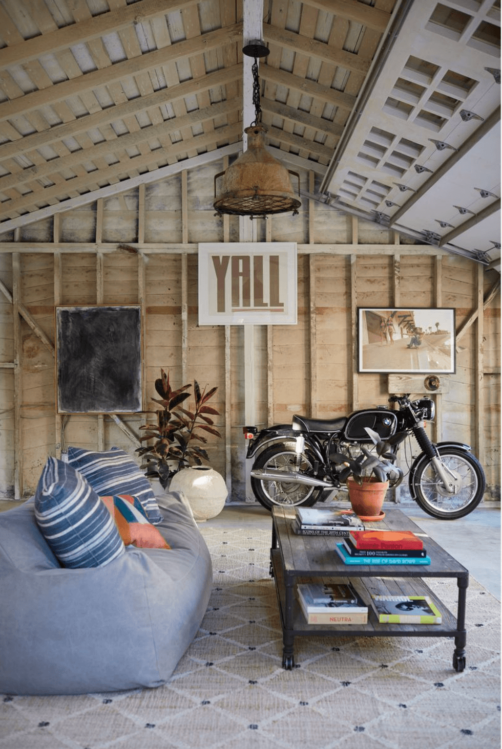 Vintage motorcycle in cozy, rustic room with "YALL" sign.