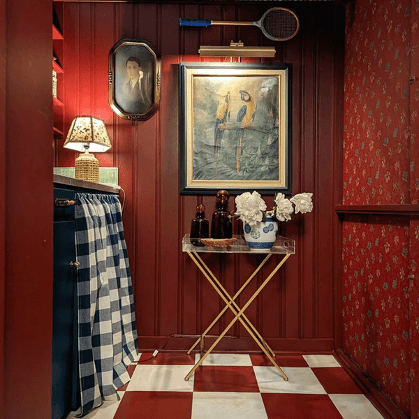 Vintage room with red walls, checkered floor, parrot painting, and blue patterned decor.