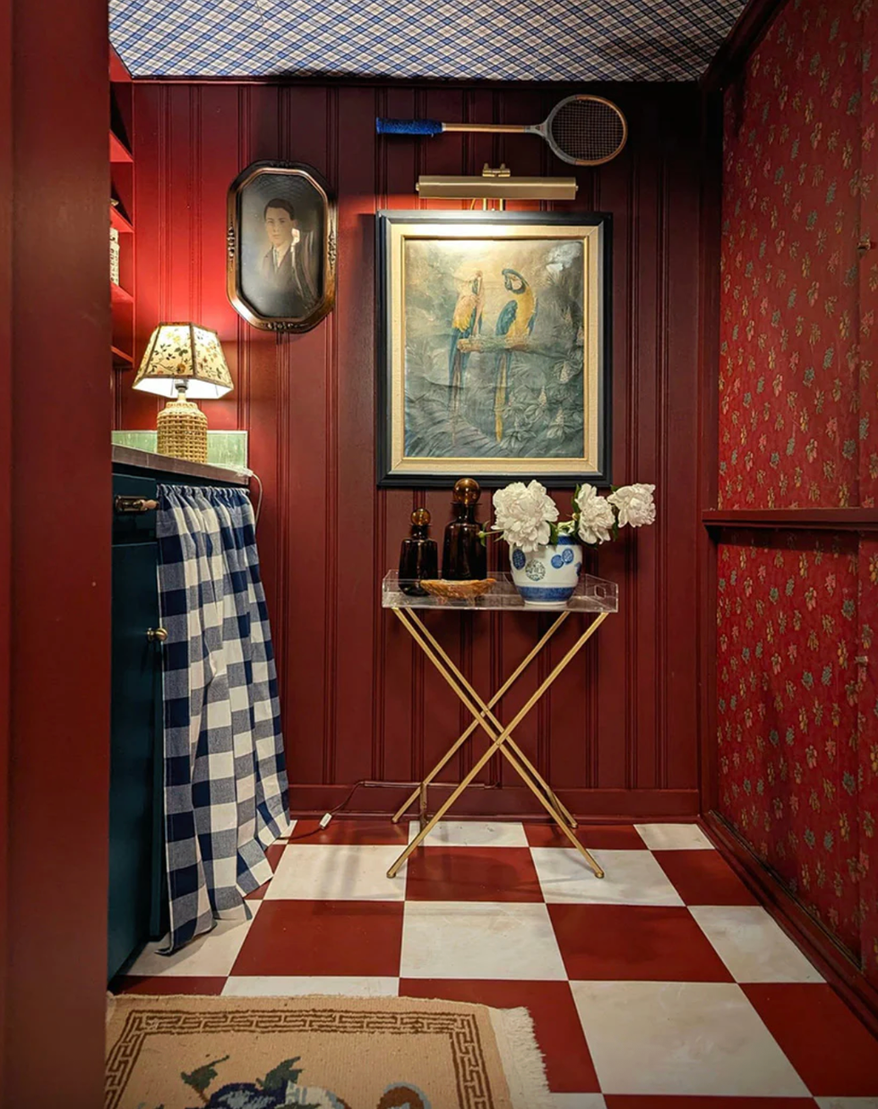 Vintage room with red walls, checkered floor, parrot painting, and blue patterned decor.
