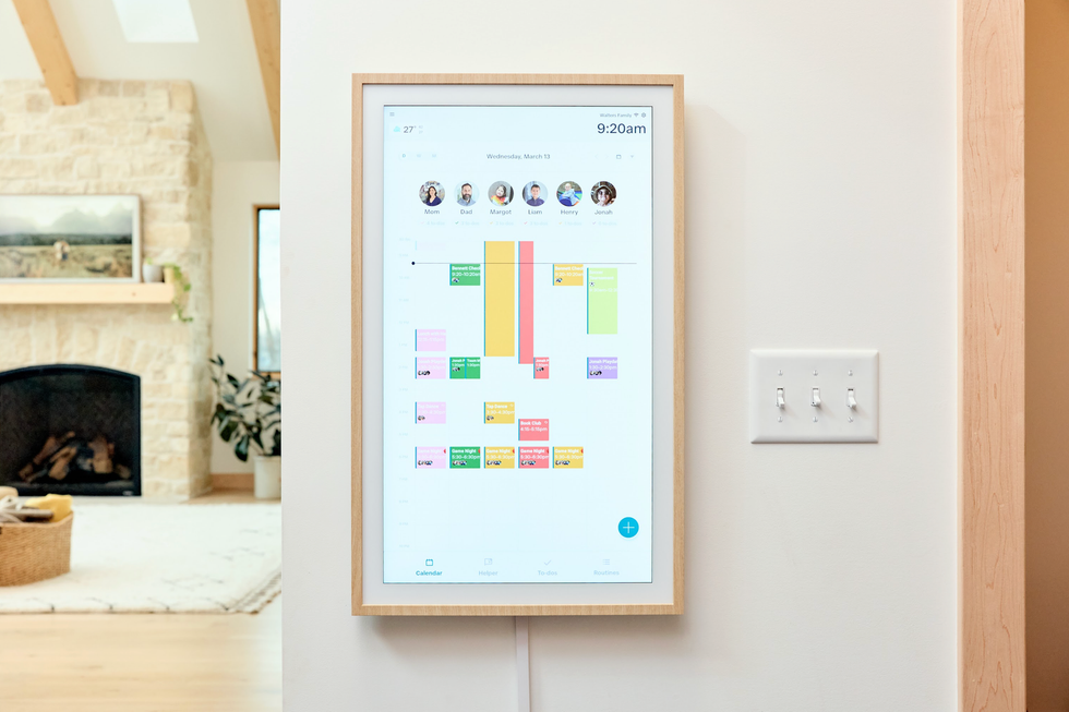 Wall-mounted digital family calendar in a modern living room setting.