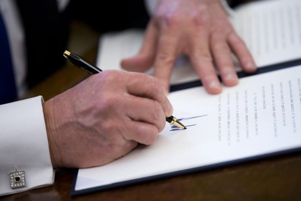 WASHINGTON, DC - JANUARY 24: US President Donald Trump signs one of five executive orders related to the oil pipeline industry in the Oval Office of the White House January 24, 2017 in Washington, DC. President Trump has a full day of meetings including one with Senate Majority Leader Mitch McConnell and another with the full Senate leadership. (Photo by Shawn Thew-Pool/Getty Images)