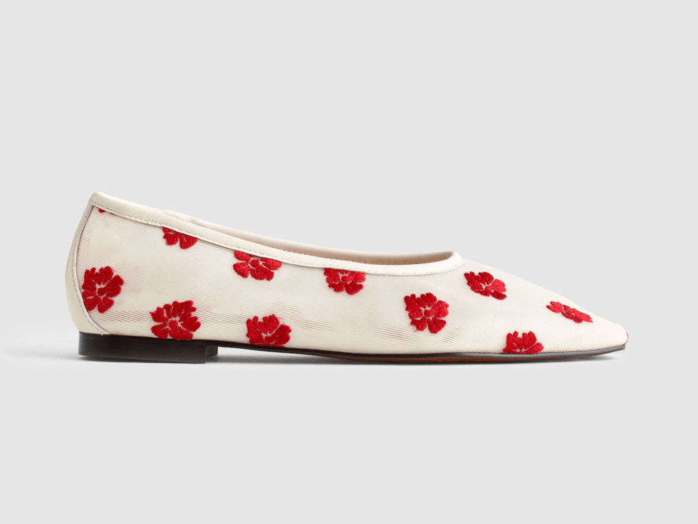 White flat shoe with red floral embroidery on a gray background.