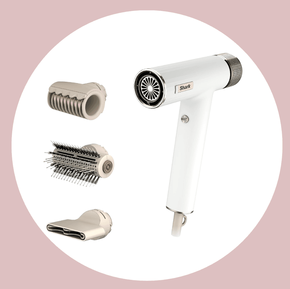 White hair dryer with three beige attachments on a pink background.