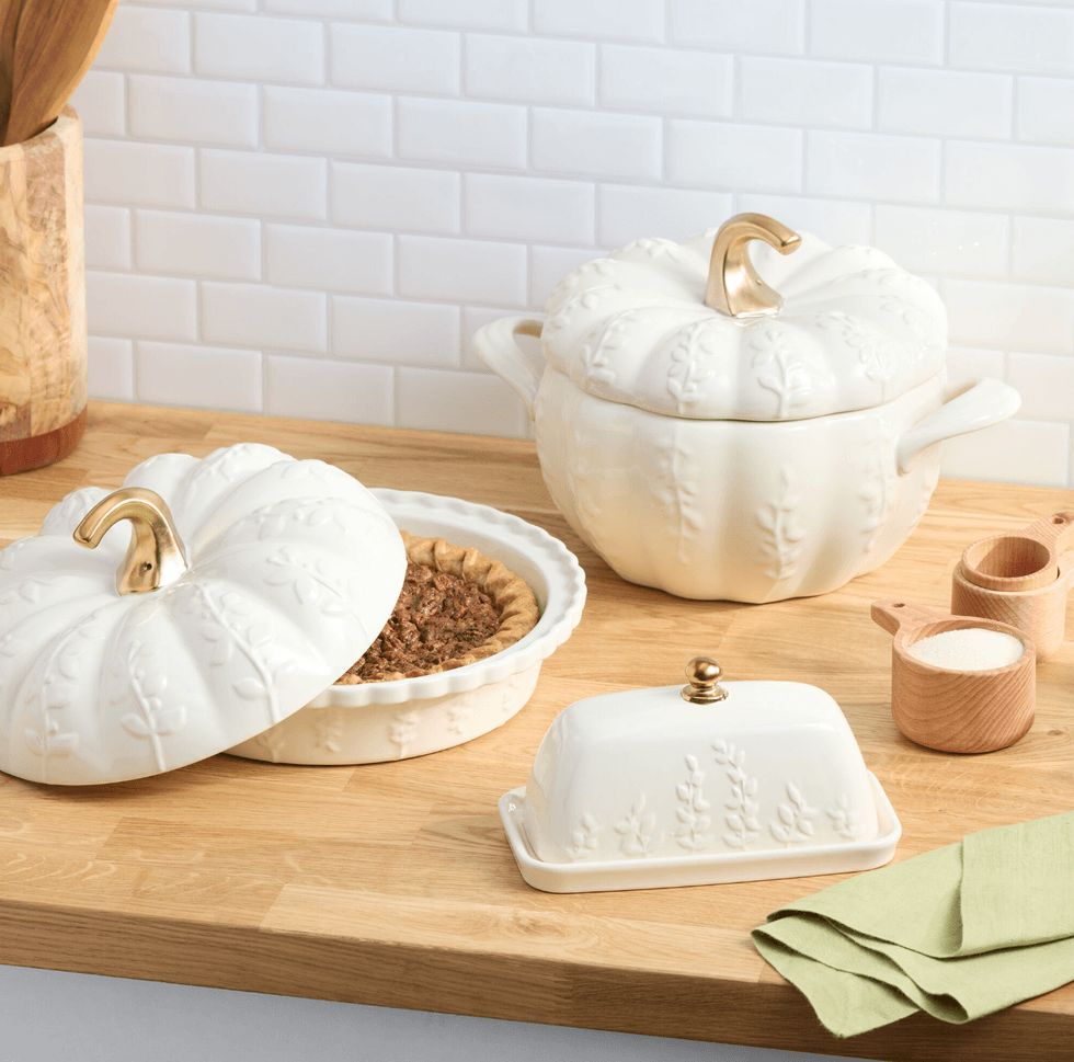 White pumpkin-shaped ceramic dishware on a wooden kitchen counter.