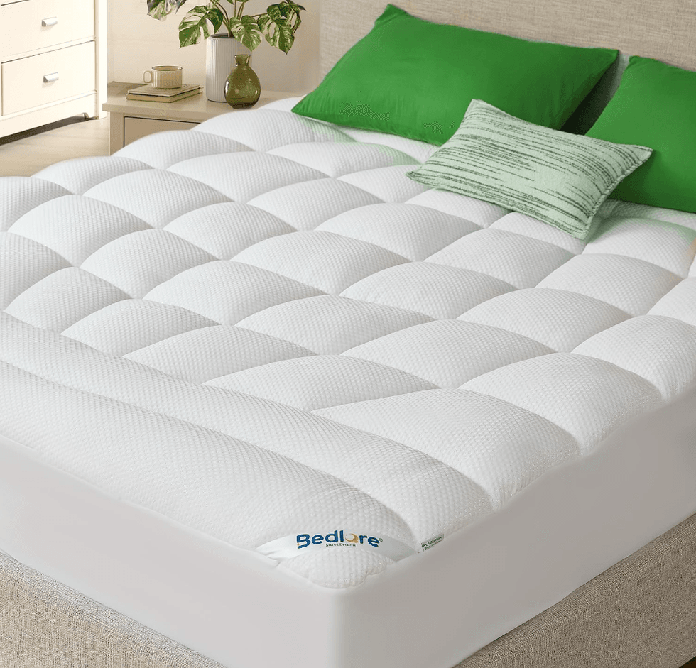 White quilted mattress topper with green pillows on a bed.
