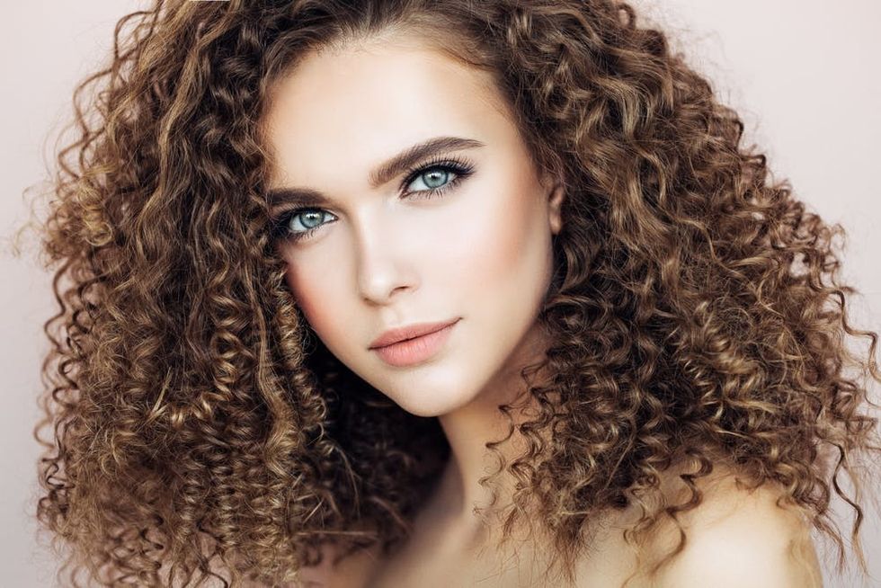 White woman with blue eyes and curly brown hair.