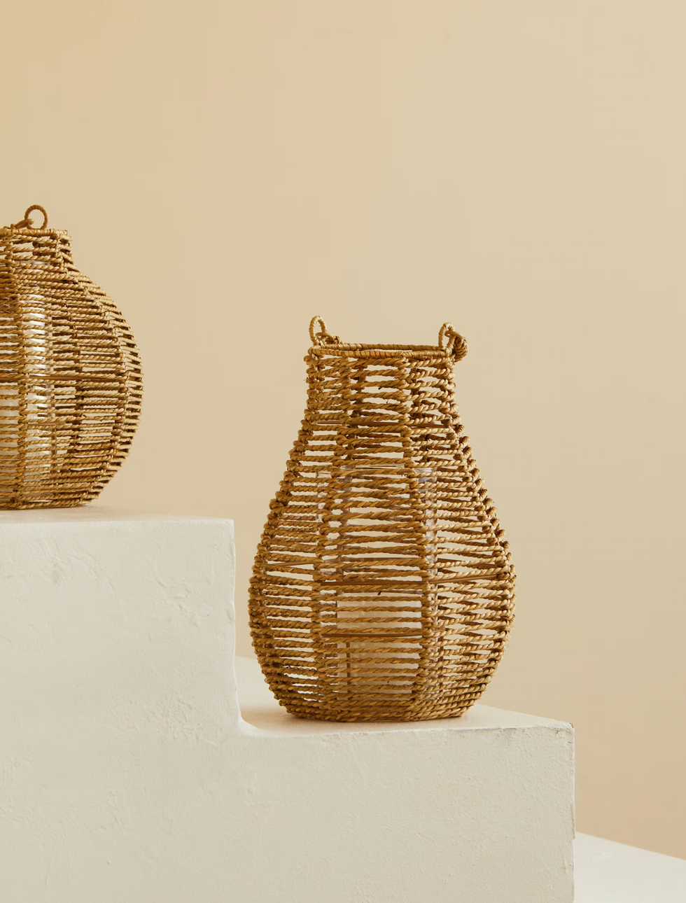 Wicker baskets on white stepped platform against beige background.