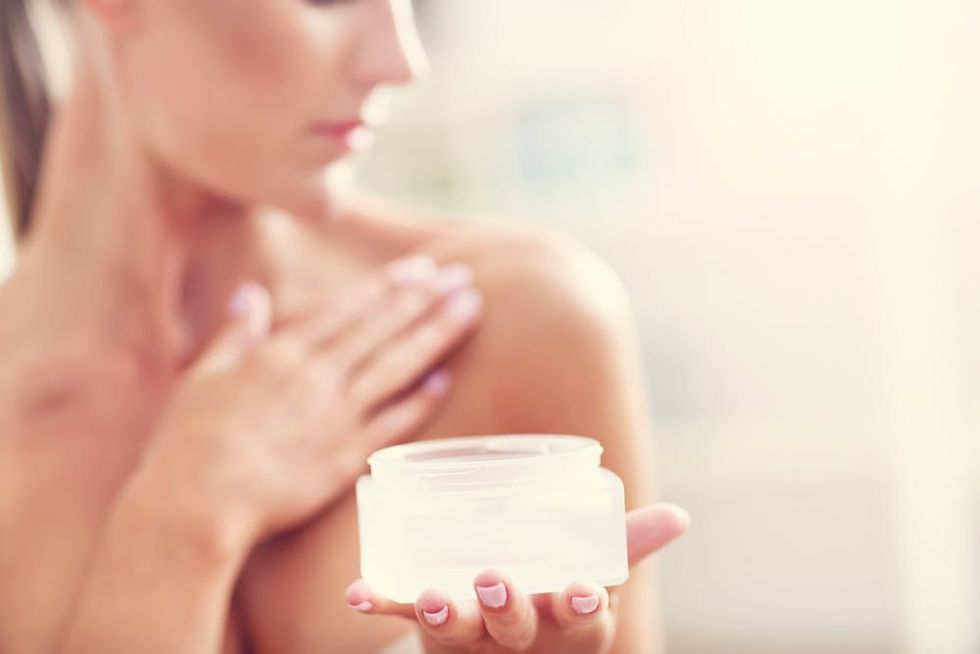 Woman applying cream to her chest. 
