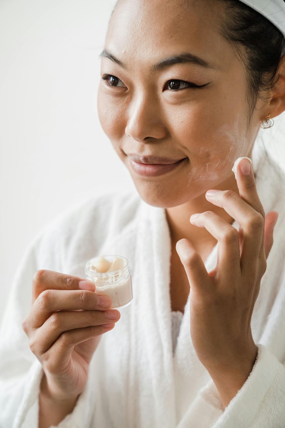 woman applying moisturizer to face
