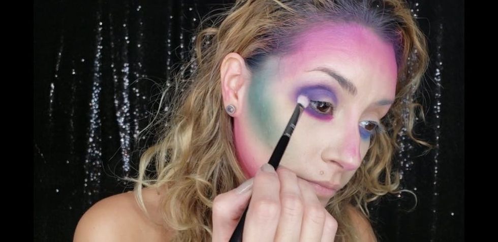 Woman applying purple eye makeup.