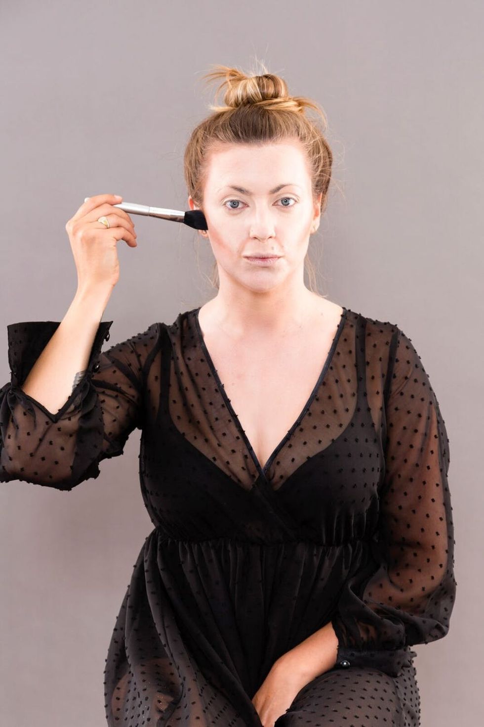 Woman applying second shade of bronzer. 