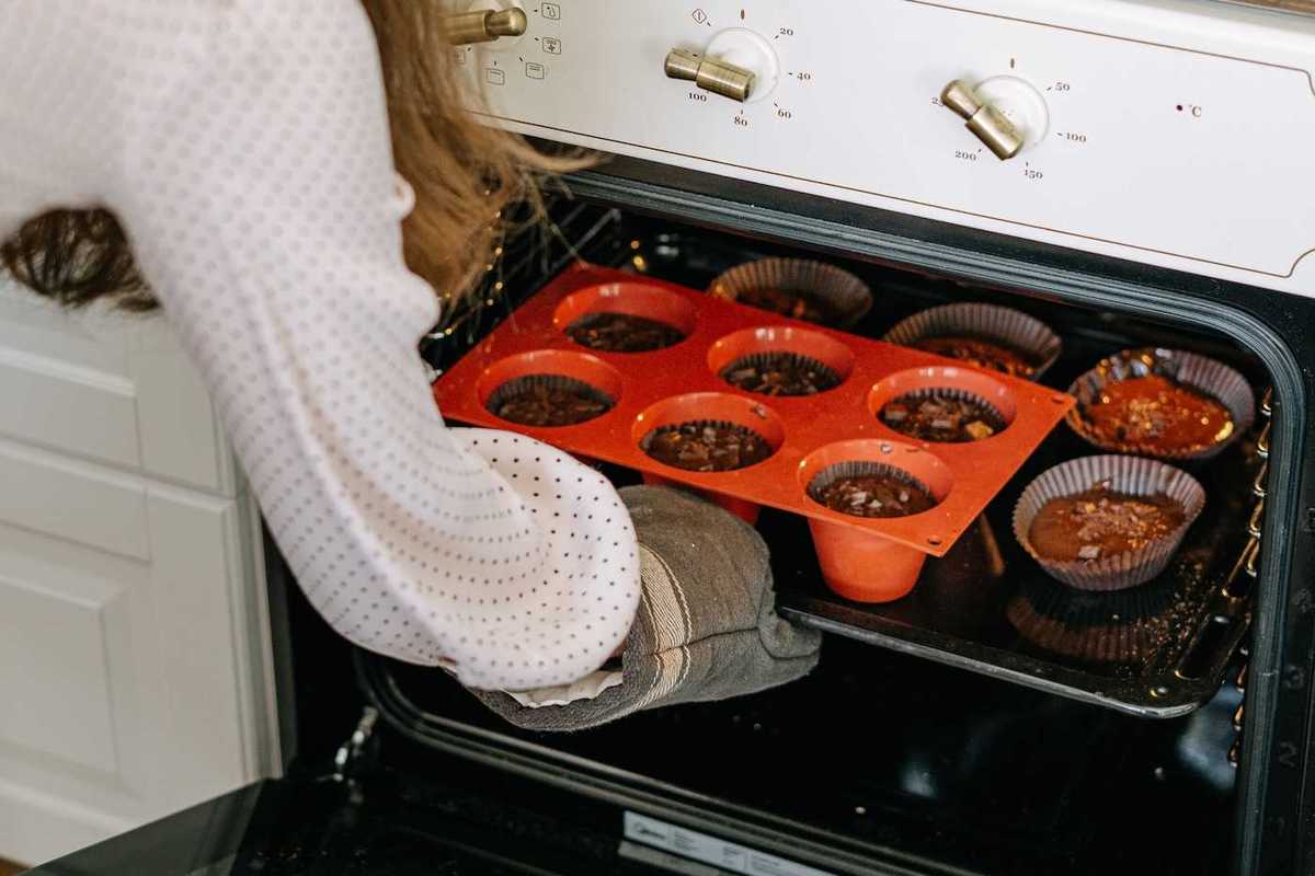 woman baking muffins in the oven in the fall