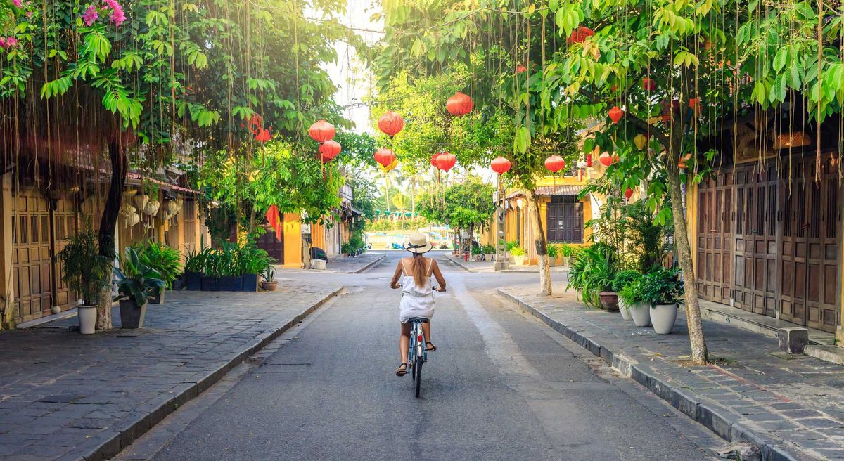 Woman cycling through the lantern-lined streets of Hoi An, Vietnam