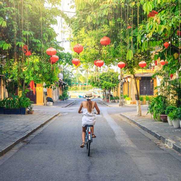 Woman cycling through the lantern-lined streets of Hoi An, Vietnam
