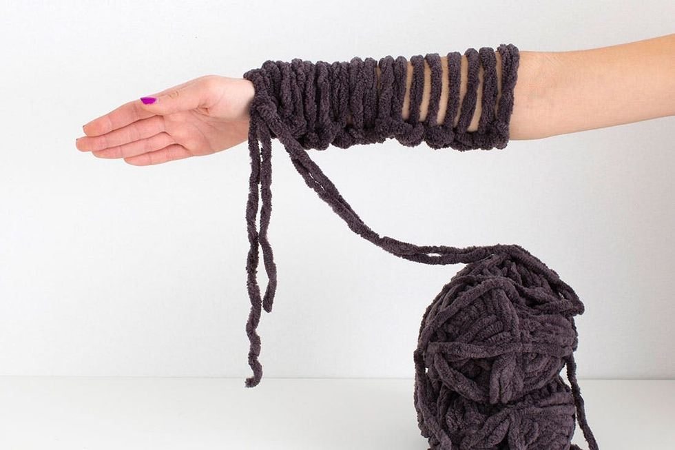 woman demonstrating how to knit a scarf