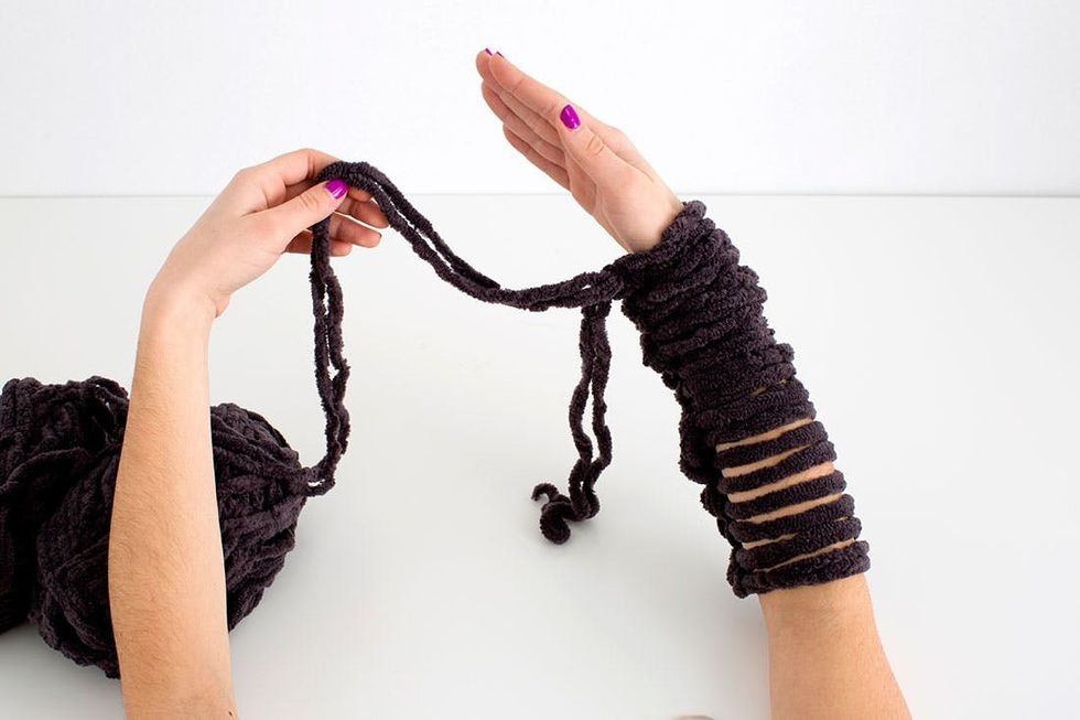 woman demonstrating how to knit a scarf