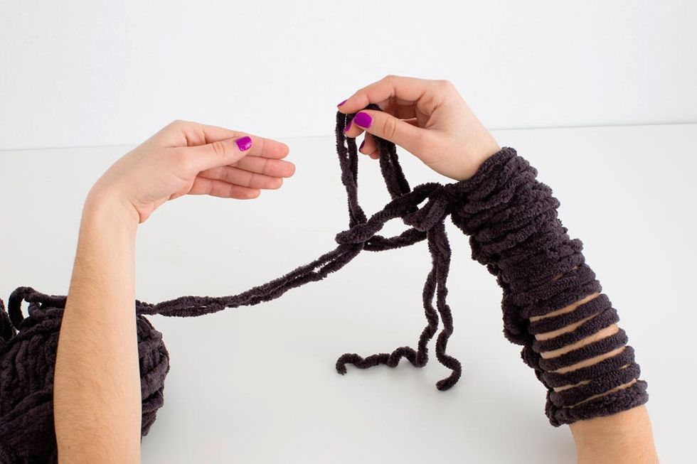 woman demonstrating how to knit a scarf