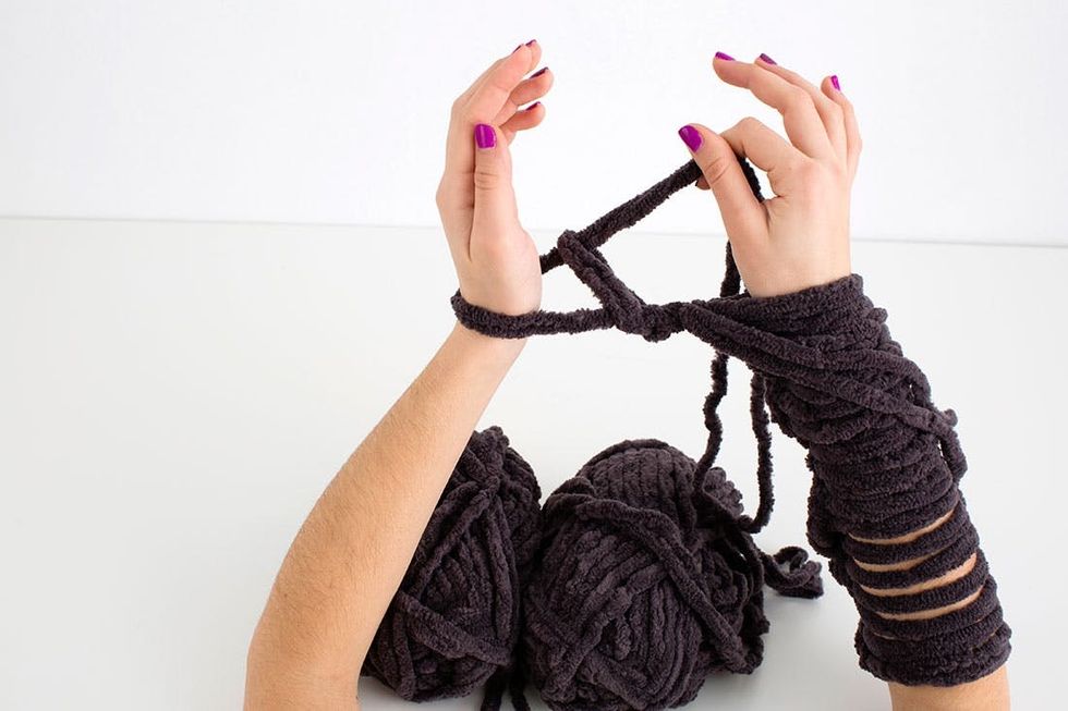 woman demonstrating how to knit a scarf