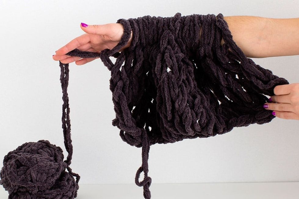 woman demonstrating how to knit a scarf