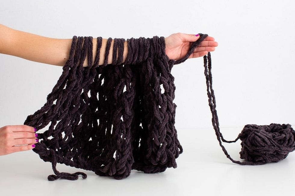 woman demonstrating how to knit a scarf