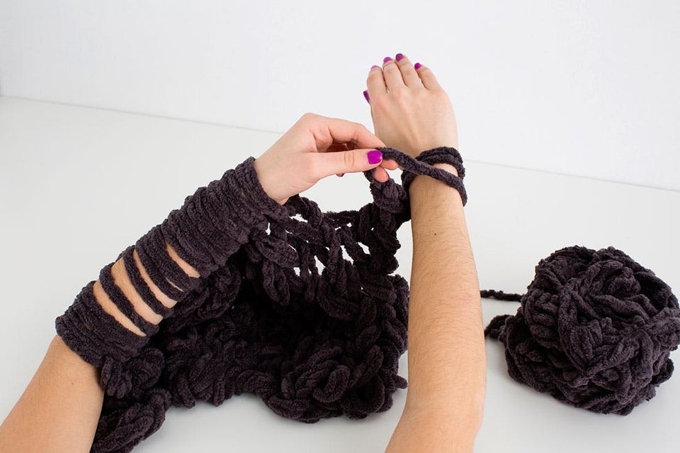 woman demonstrating how to knit a scarf