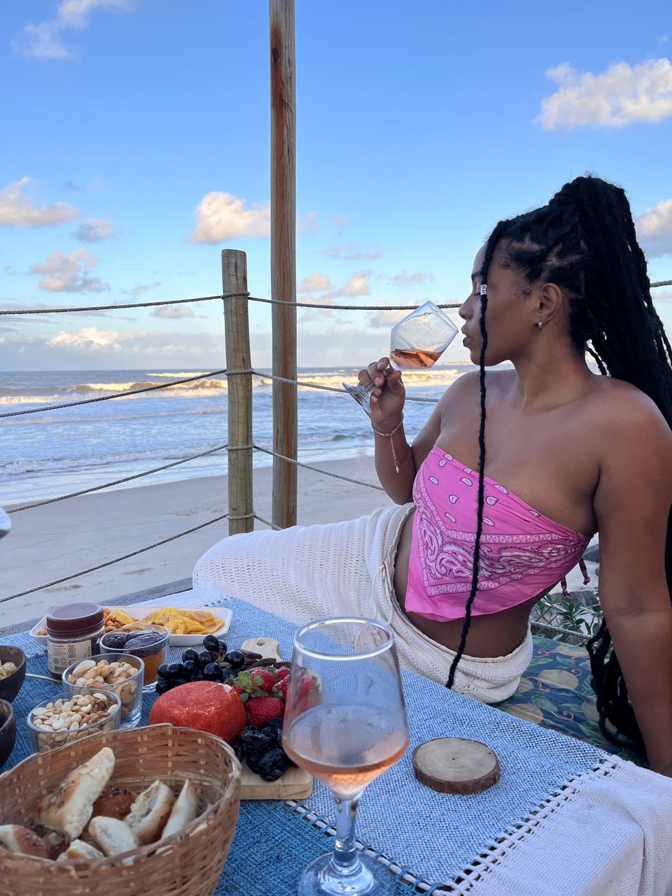 woman eating snacks and sipping rose at a beach-front table