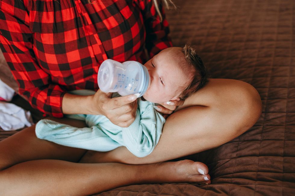woman feeding infant baby bottle