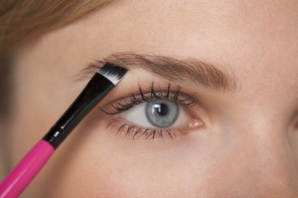 Woman filling in her eyebrow with an angled brush.