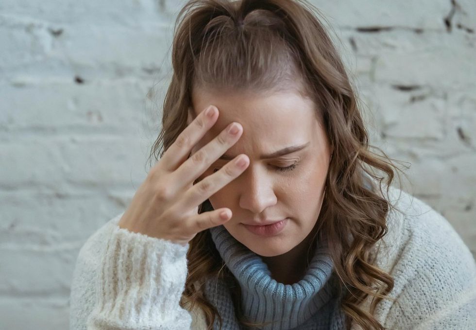 woman grimacing with her face in her hand
